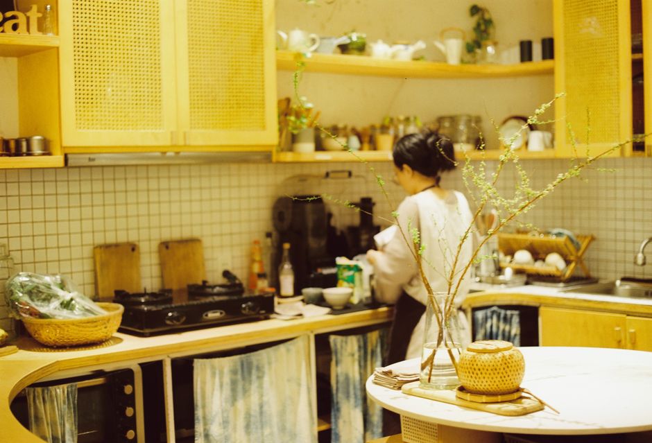 A woman prepares food in a warm, rustic kitchen setting, showcasing domestic life and home cooking.
